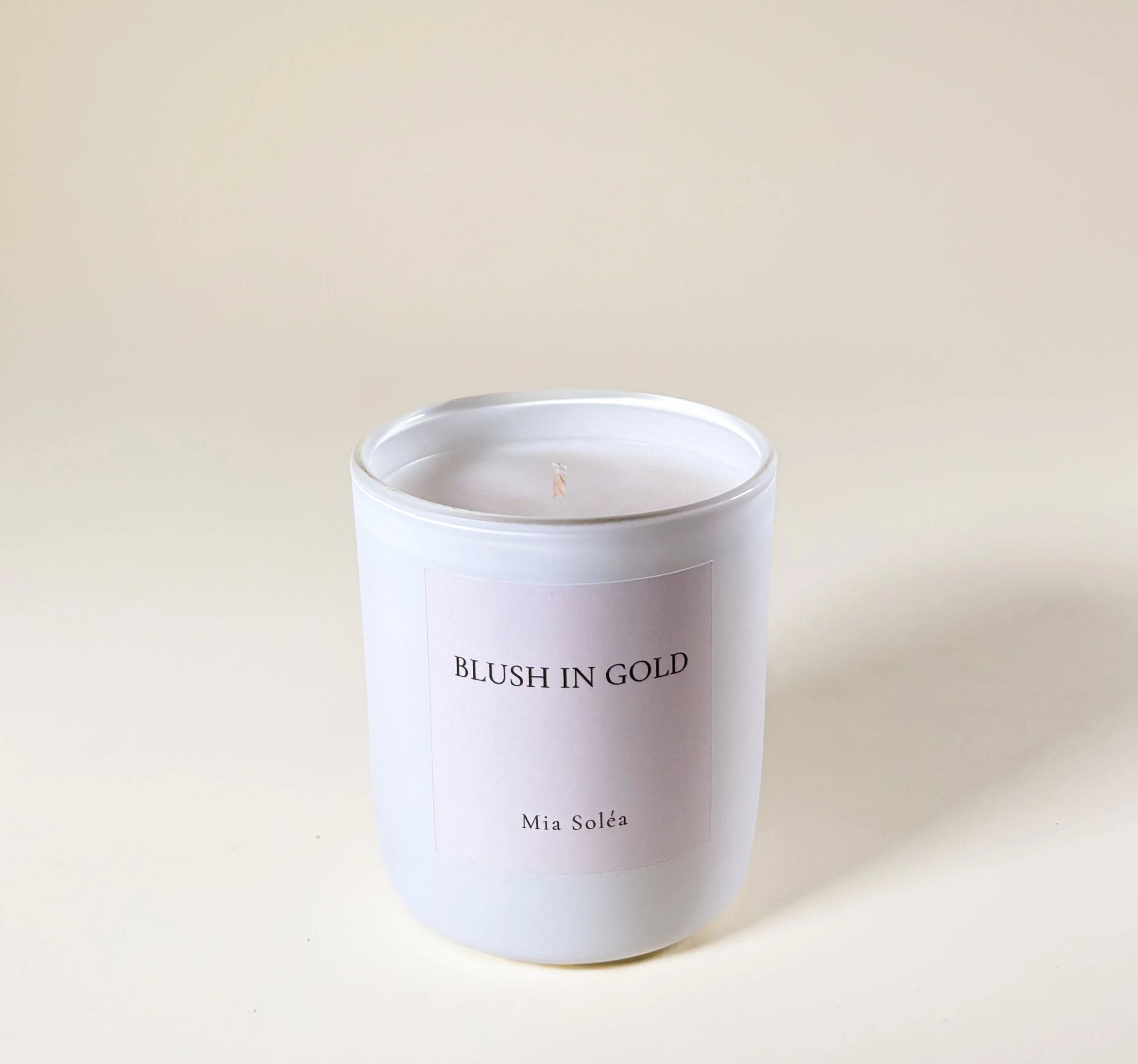 Blush in Gold Duftkerze von Mia Soléa auf hellem Hintergrund. Warmer floraler Duft mit Damaskrose, Oud und sanften Gourmandnoten.