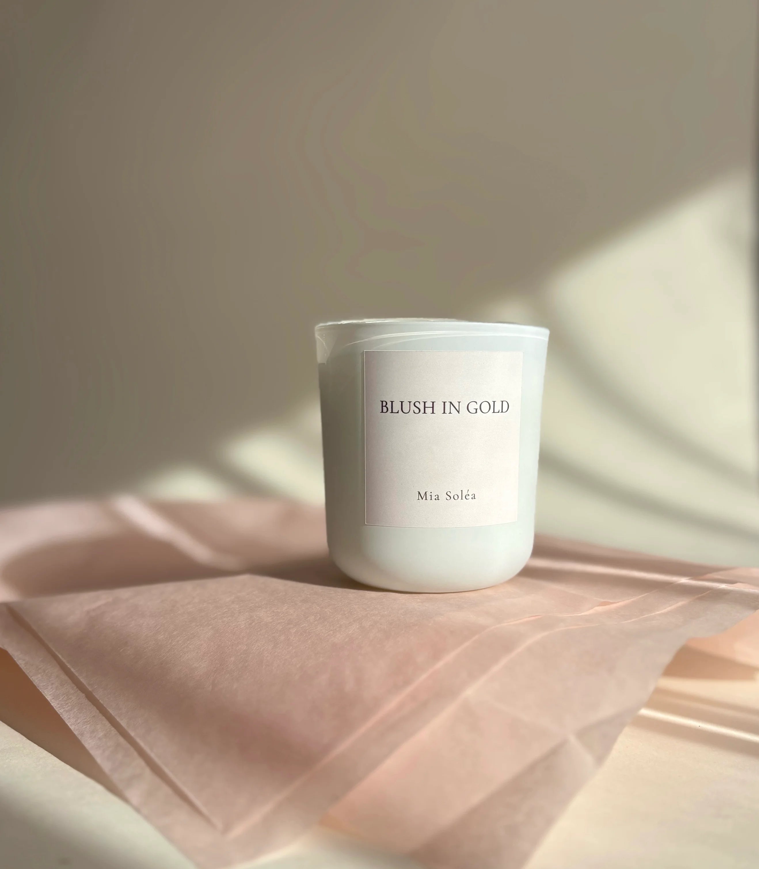 Duftkerze „Blush in Gold“ auf zartem Seidenpapier mit weichem Licht – elegante, feminine Atmosphäre
