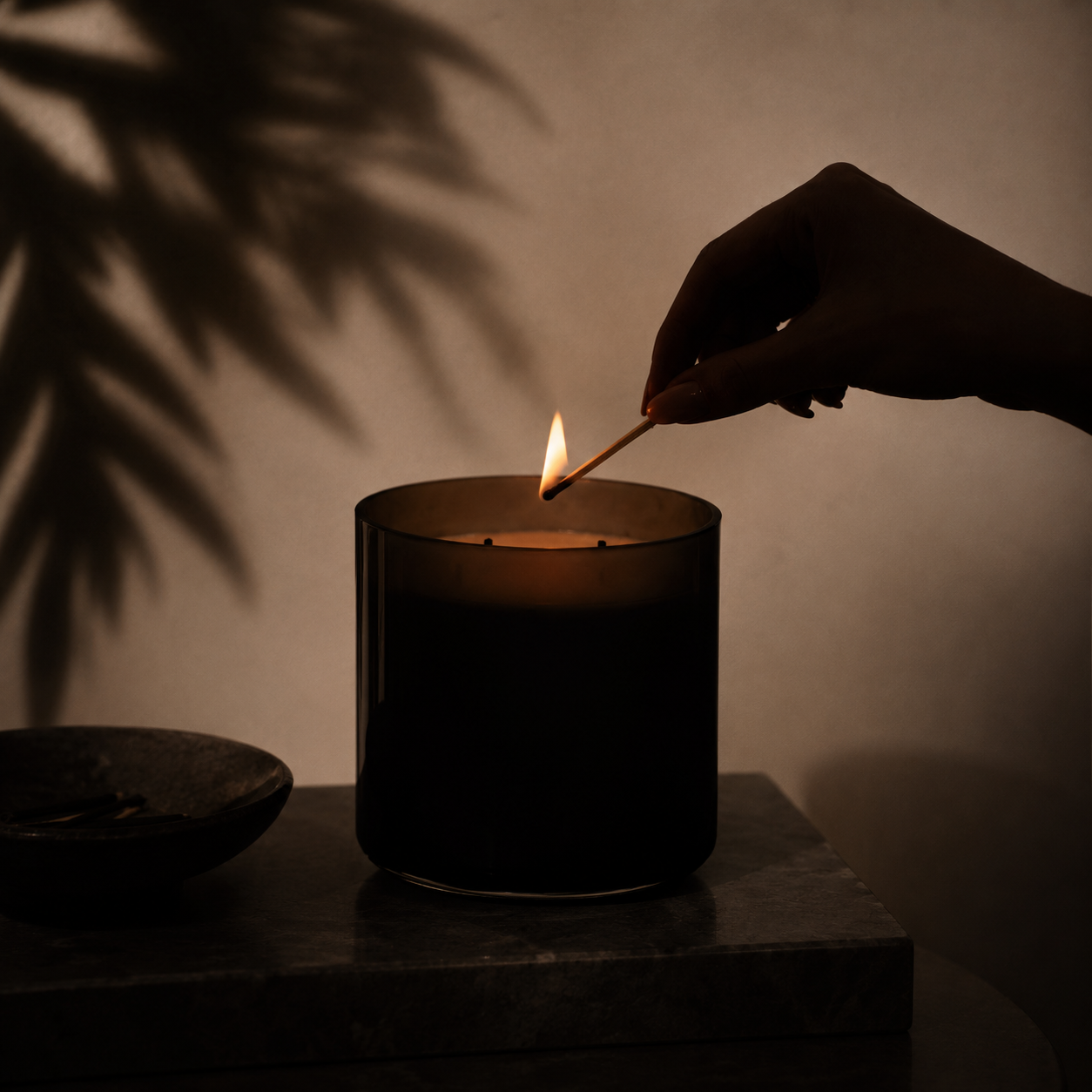 Editorial-Aufnahme einer Duftkerze im warmen Abendlicht. Das Bild zeigt den Moment des Anzündens mit einem Streichholz und unterstreicht das Thema Kerzenpflege und Candle Care.